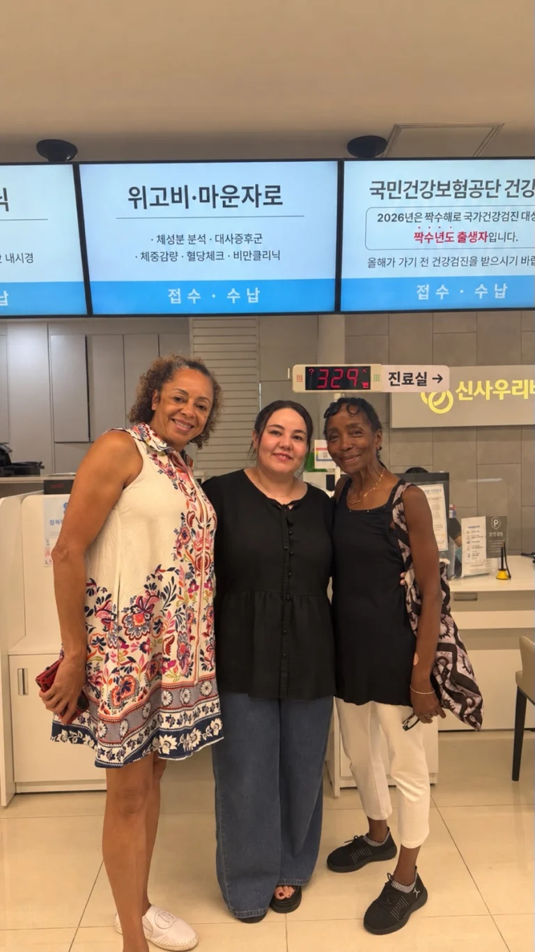 Two patients smiling with our coordinator at the reception of Sinsa Woori Best Internal Medicine Clinic in Seoul