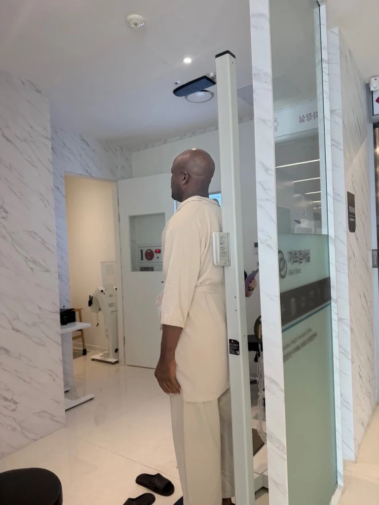 A patient on the height and weight scale in a bright examination room
