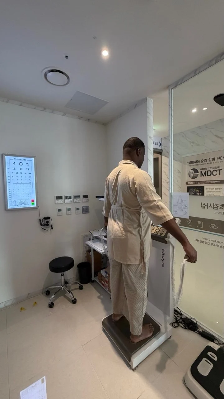 A patient in a check-up gown on the body composition analyser