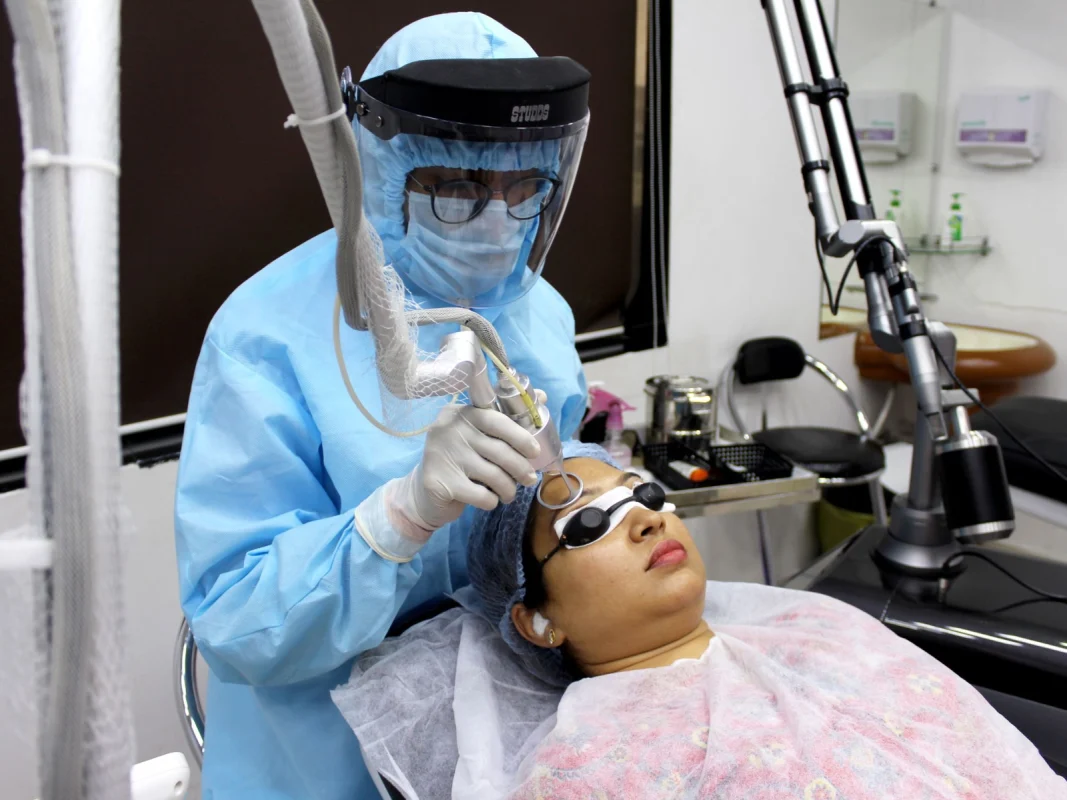A practitioner performs a laser skin treatment on a patient wearing eye protection